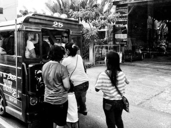 Black and white photo of people getting on a train.