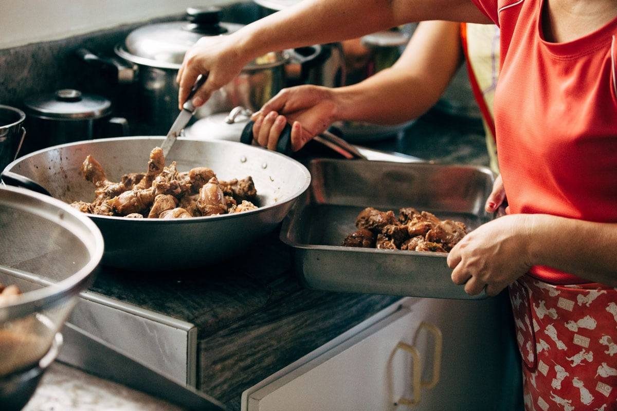 Woman filling a pan with food to serve.