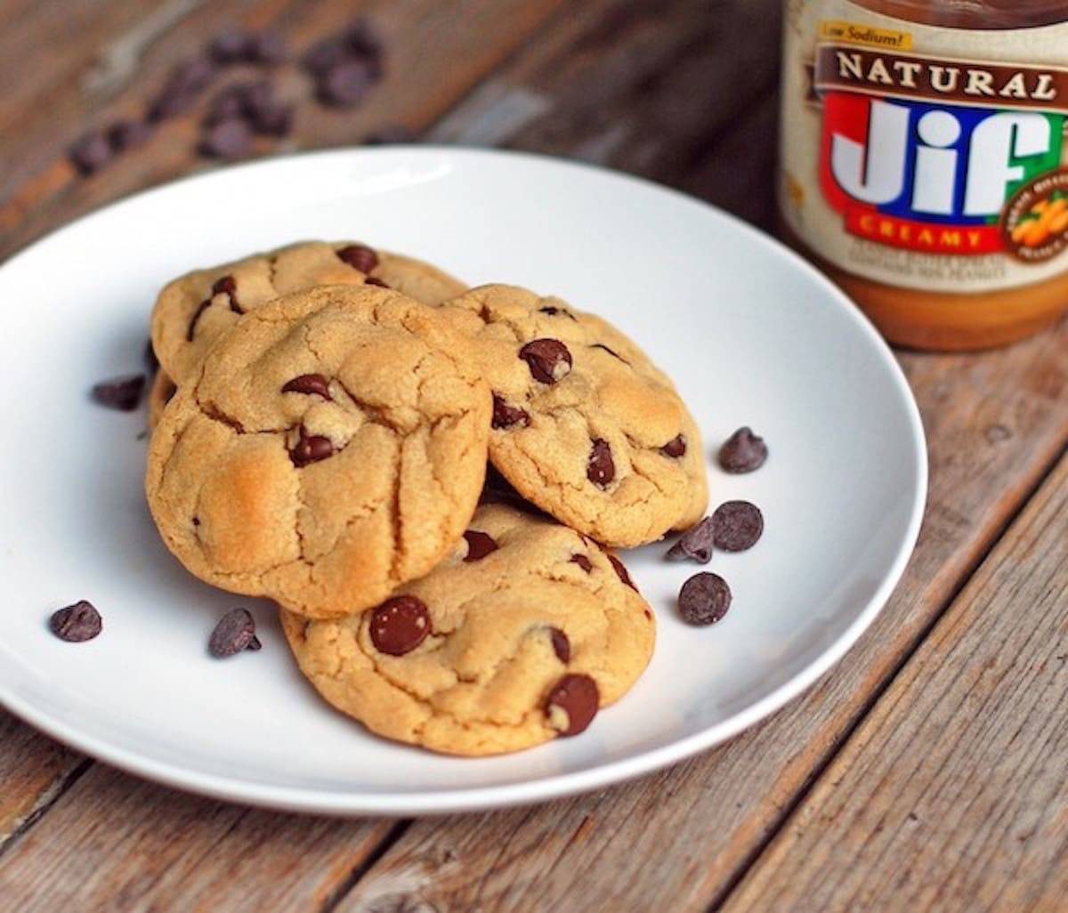 Peanut Butter Chocolate Chip cookies on a plate near peanut butter.
