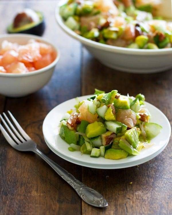 Avocado cucumber grapefruit salad on a plate with a fork.