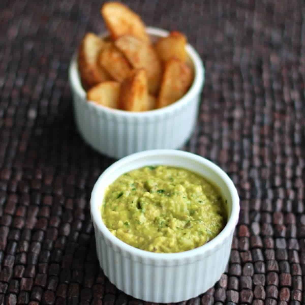 Avocado tomatillo dip in a white dish.