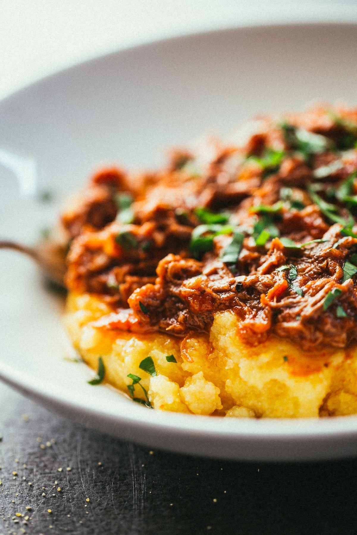 Crockpot Braised Beef Ragu with Polenta on a white plate.