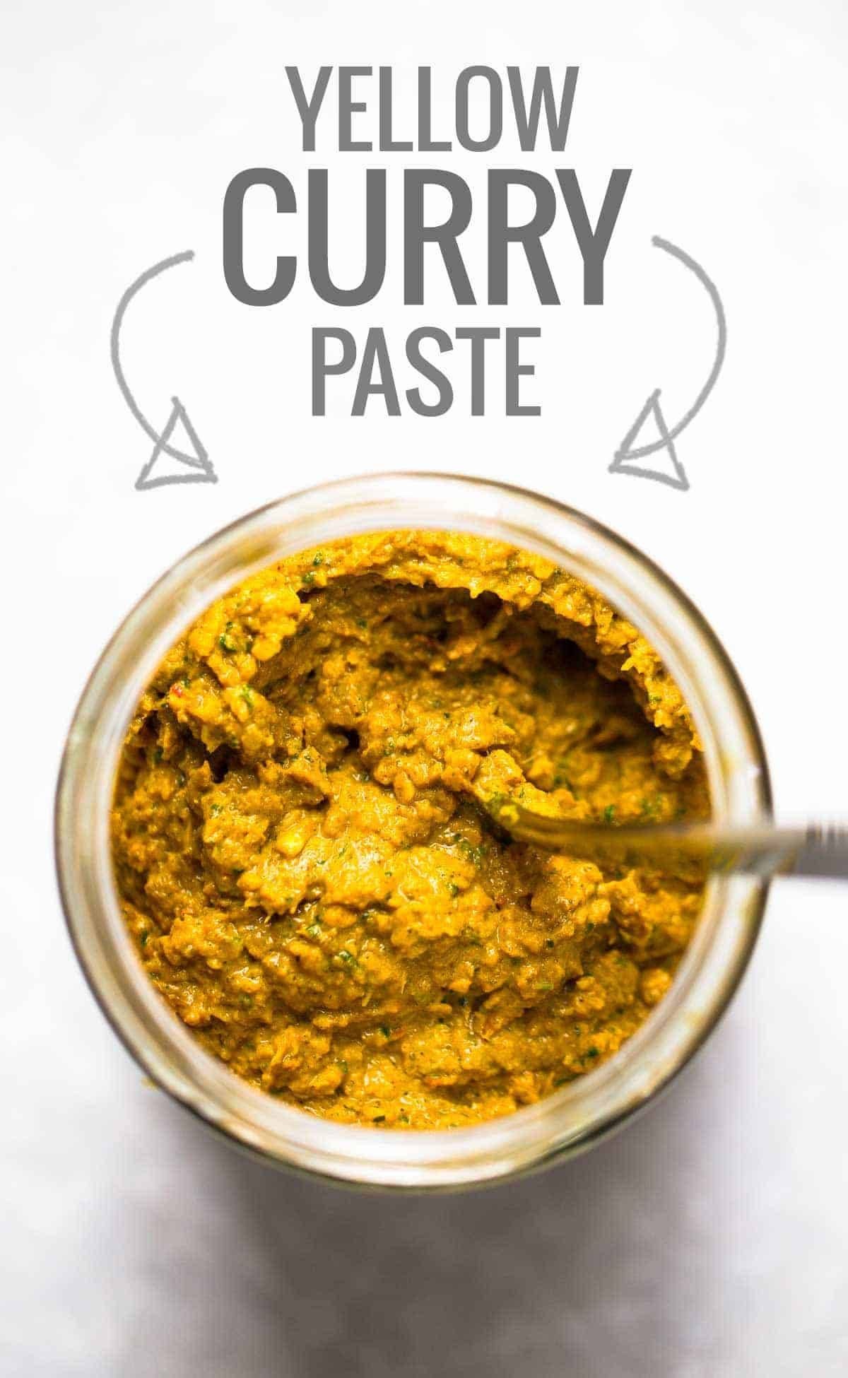 Homemade yellow curry paste in a jar with a spoon.