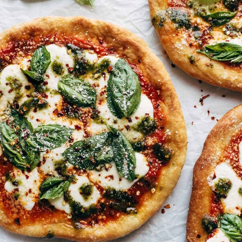Fried Pizzas on parchment paper with basil.