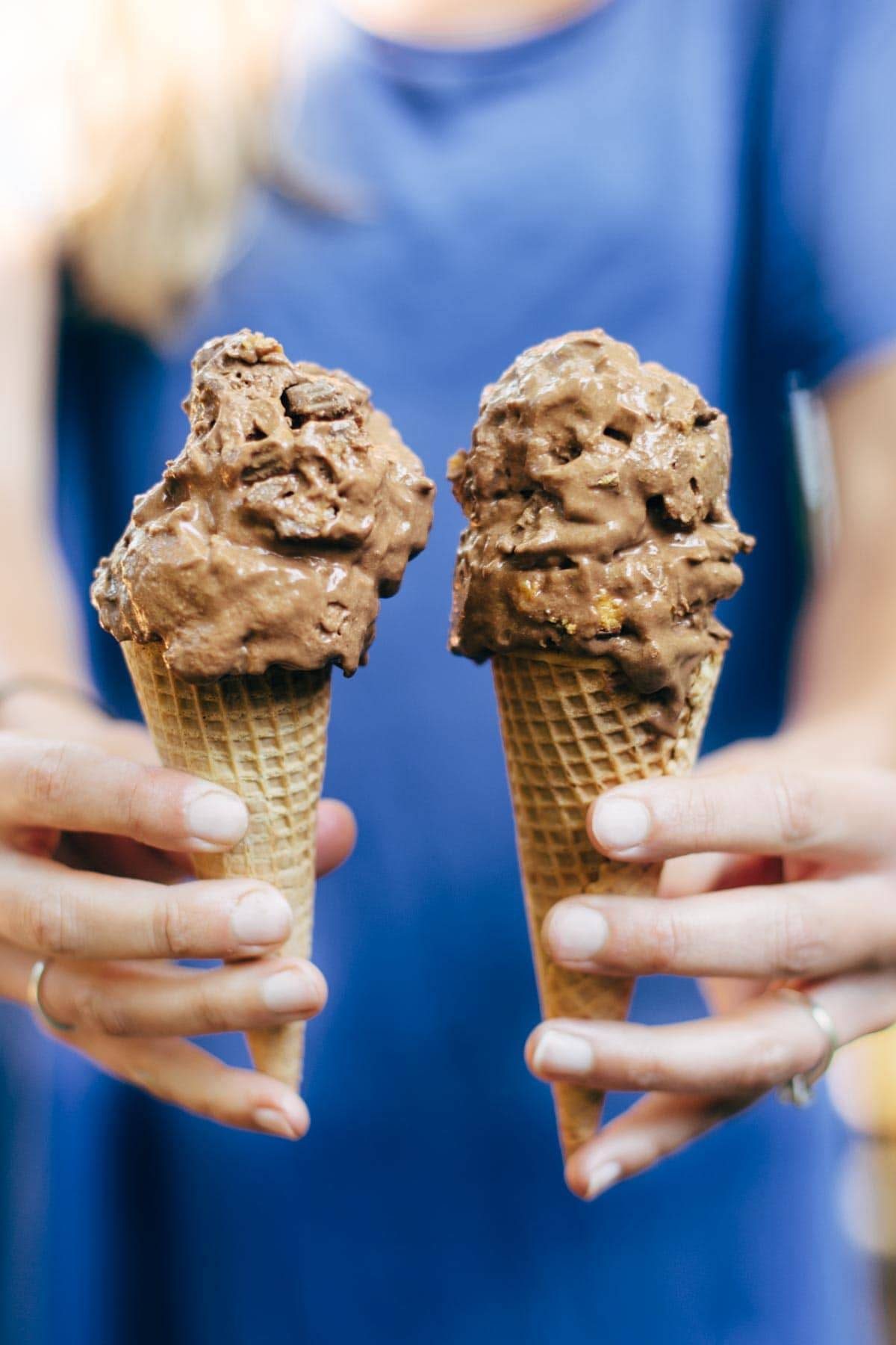 Hands holding cones of nice cream.
